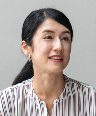 A smiling woman with dark hair is looking to camera.