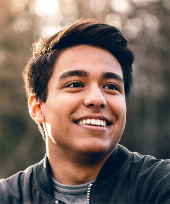 A young man smiles at the camera with a big, happy smile.
